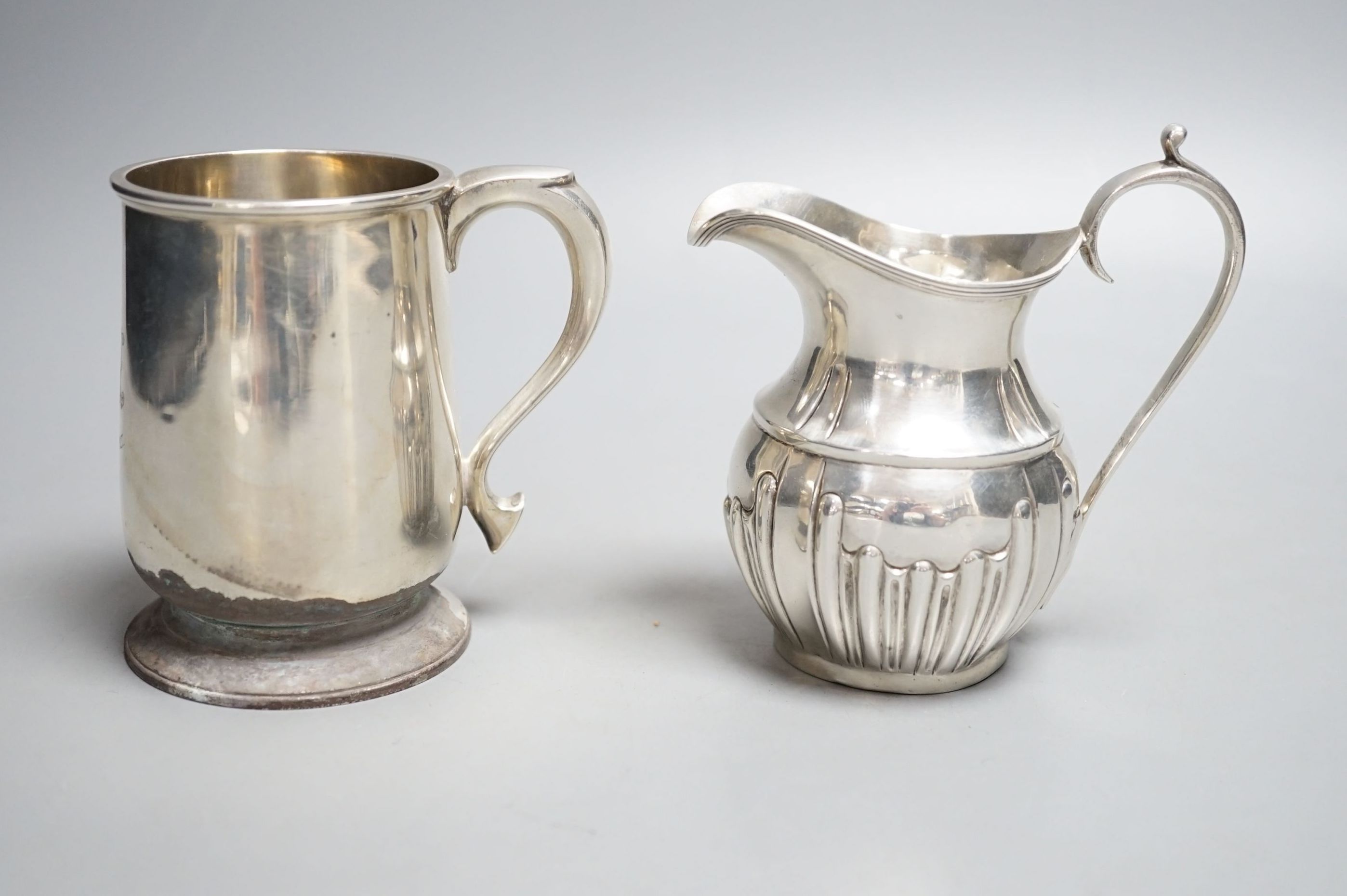 A late Victorian silver cream jug, Nathan & Hayes, Chester, 1897 and a George V silver christening mug, William Hutton & Sons, Sheffield, 1924
